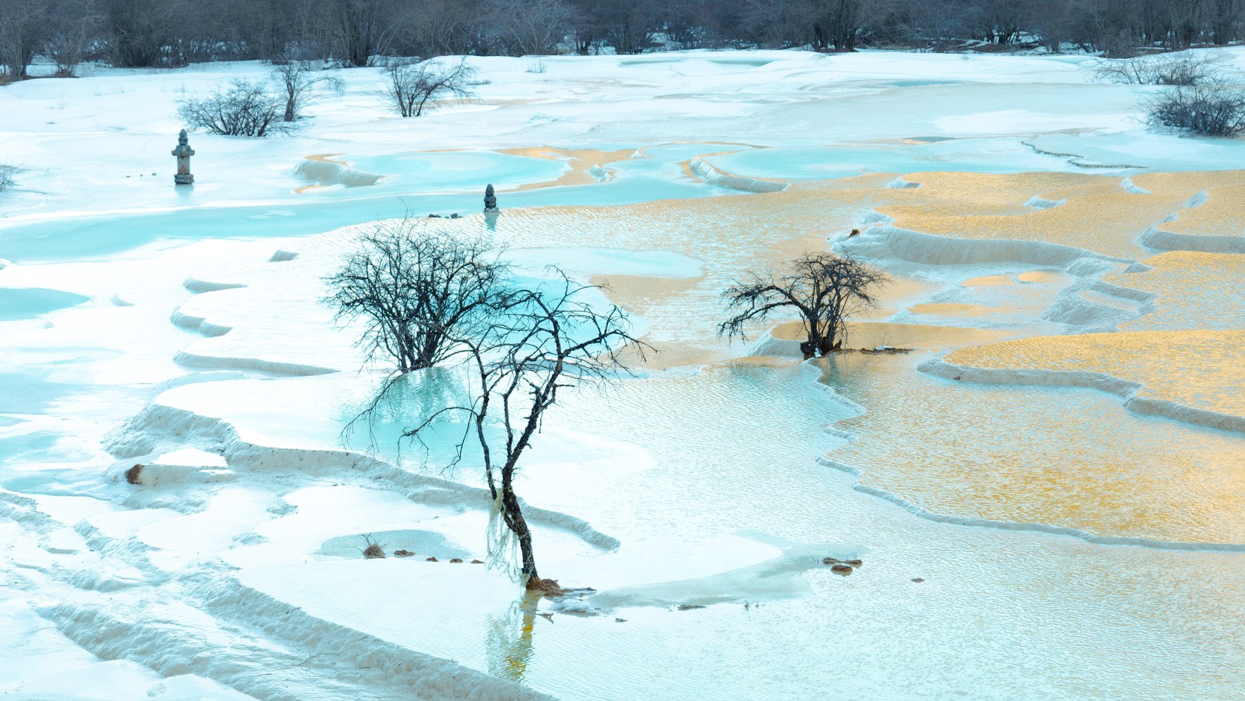冬季雪地中的蓝绿色与金色钙华彩池